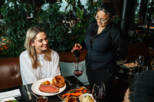 waitress pours wine for woman eating sunday roast