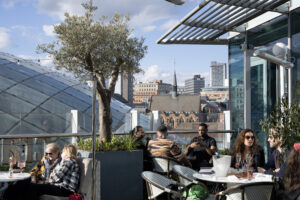 people sitting at restaurant terrace with leeds city centre view behind