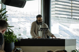 dj playing music at restaurant event with leeds city centre view behind