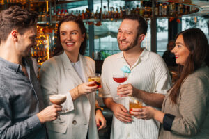 people holding cocktails and smiling at rooftop restaurant and bar